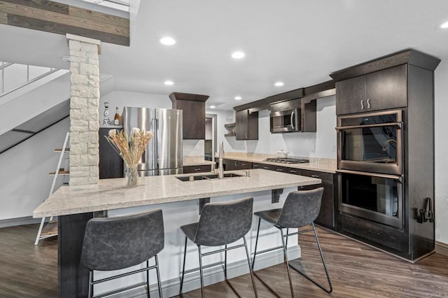 3404 Oak Cliff Dr Unit 8, Fallbrook, CA 92028 - kitchen featuring stainless steel appliances, a sink, ornate columns, dark brown cabinetry, and dark wood-style flooring