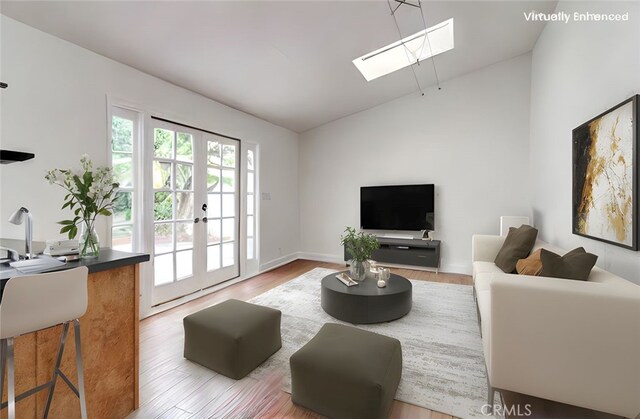 9341 Grand Dr, Huntington Beach, CA 92646 - living room featuring a skylight, vaulted ceiling, french doors, and wood finished floors