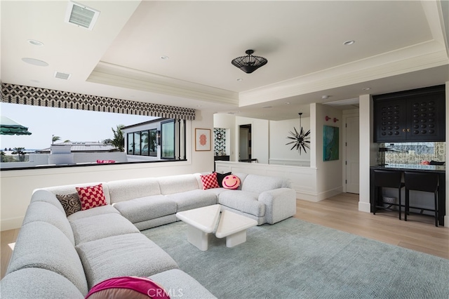 1110 Kings Rd, Newport Beach, CA 92663 - living area featuring a raised ceiling, light wood finished floors, crown molding, a community bar, and baseboards