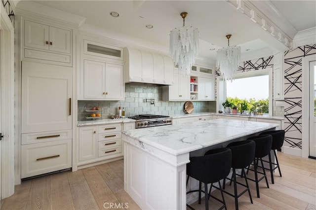 1110 Kings Rd, Newport Beach, CA 92663 - kitchen with light wood-style flooring, a kitchen island, decorative backsplash, light stone counters, and glass insert cabinets