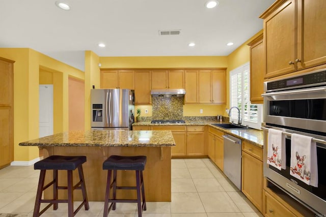 907 Rockwell Springs Ct, Escondido, CA 92025 - kitchen with appliances with stainless steel finishes, a sink, a kitchen island, under cabinet range hood, and a breakfast bar