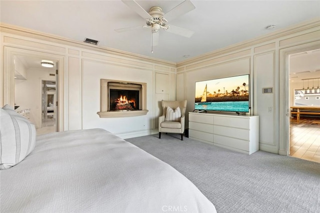 218 Evening Star Ln, Newport Beach, CA 92660 - bedroom with a decorative wall, a lit fireplace, ceiling fan, crown molding, and light carpet