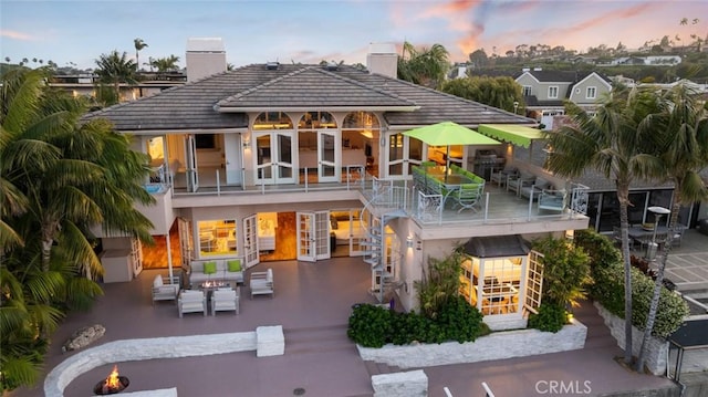218 Evening Star Ln, Newport Beach, CA 92660 - back of property at dusk with stairway, a chimney, a patio area, and french doors