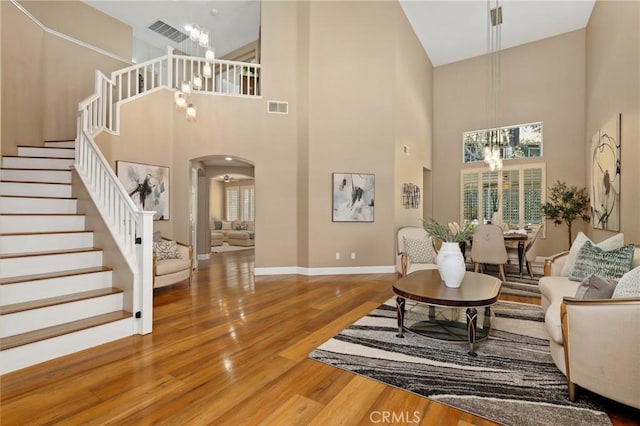 24261 Ernest Johnson Cir, Yorba Linda, CA 92887 - living room with a chandelier, stairway, wood finished floors, a towering ceiling, and healthy amount of natural light