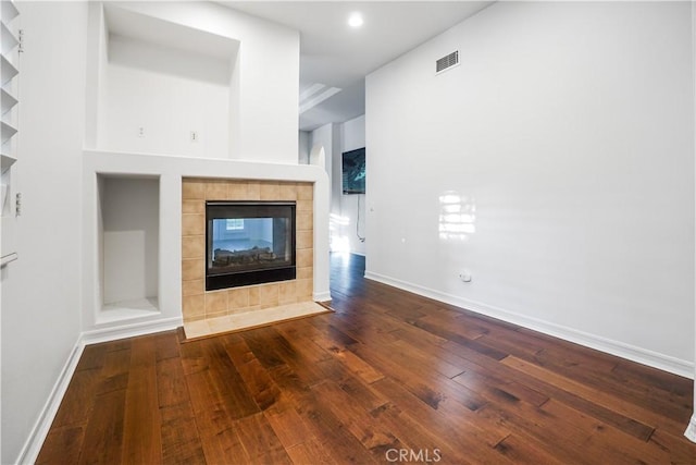12160 Glines Ct, Tustin, CA 92782 - unfurnished living room featuring a tiled fireplace, dark wood-type flooring, baseboards, built in shelves, and recessed lighting