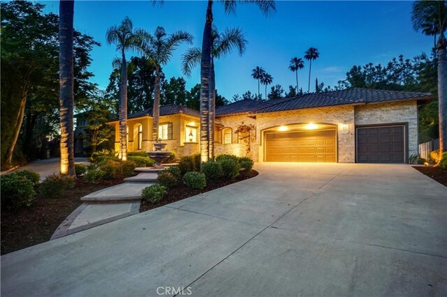 12160 Glines Ct, Tustin, CA 92782 - view of front of home featuring stone siding, driveway, an attached garage, and a tiled roof