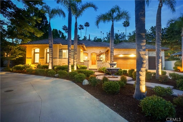 12160 Glines Ct, Tustin, CA 92782 - view of front of home featuring a garage, concrete driveway, stucco siding, and stone siding