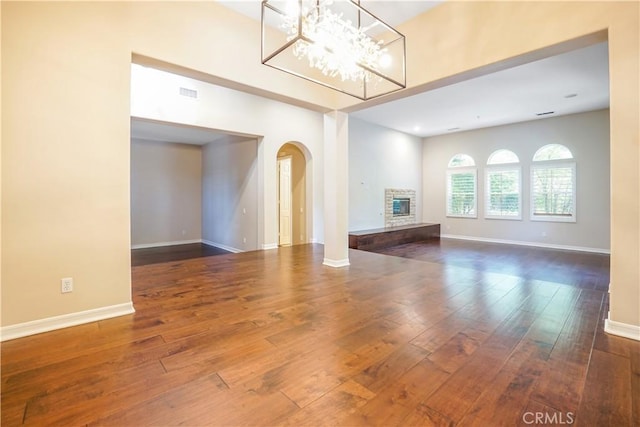 12160 Glines Ct, Tustin, CA 92782 - unfurnished living room with arched walkways, hardwood / wood-style flooring, a glass covered fireplace, and a chandelier