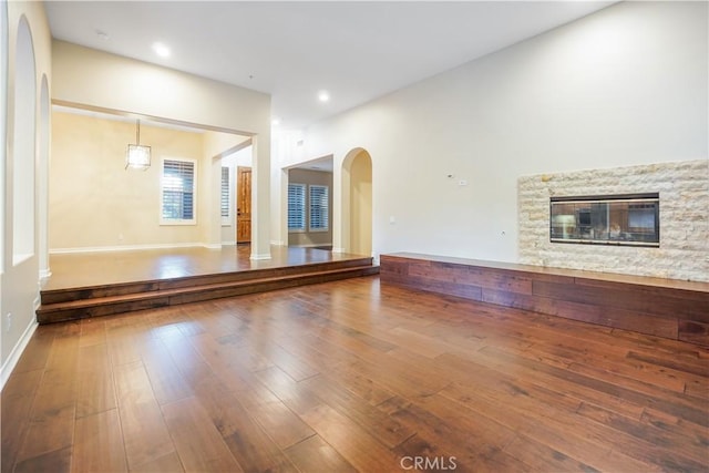 12160 Glines Ct, Tustin, CA 92782 - unfurnished living room with arched walkways, a stone fireplace, and hardwood / wood-style floors