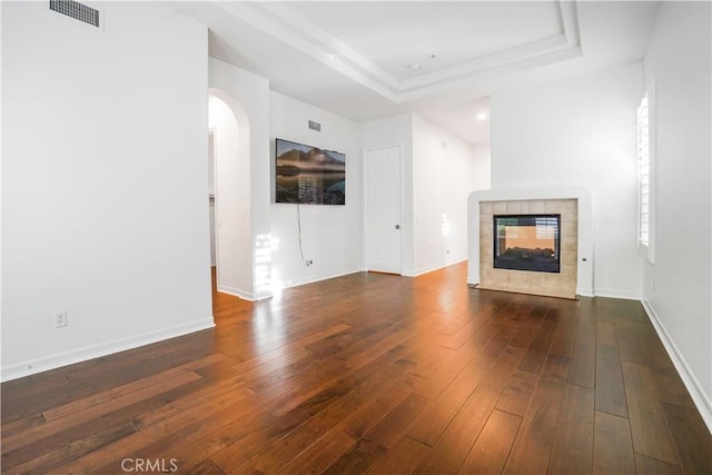 12160 Glines Ct, Tustin, CA 92782 - unfurnished living room with a fireplace, a tray ceiling, hardwood / wood-style floors, arched walkways, and baseboards
