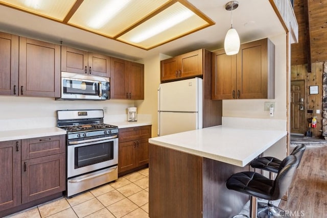 27495 Cedarwood Dr, Lake Arrowhead, CA 92352 - kitchen with stainless steel appliances, a kitchen bar, a peninsula, and light countertops