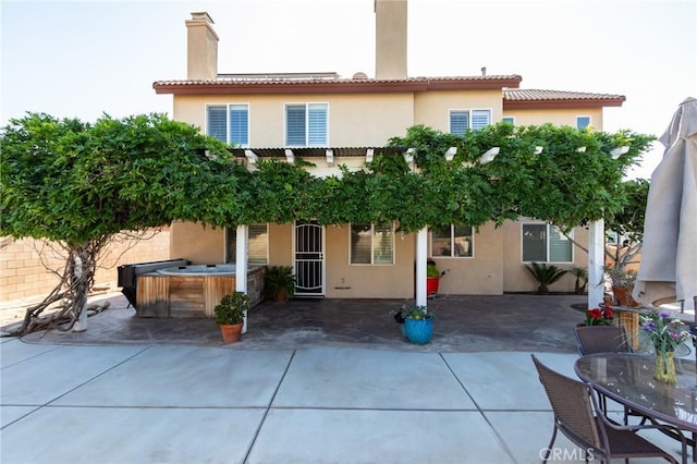 8961 Newcastle Ave, Hesperia, CA 92344 - rear view of property with a hot tub, a patio area, a chimney, and stucco siding