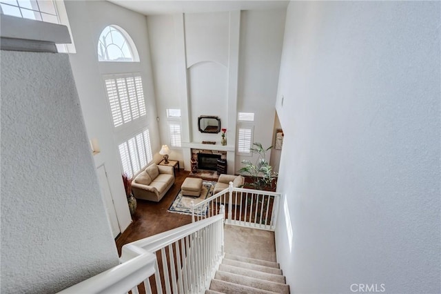 8961 Newcastle Ave, Hesperia, CA 92344 - staircase featuring a towering ceiling, carpet floors, a glass covered fireplace, and a textured wall