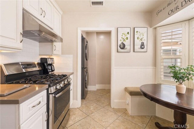 6003 Eastbrook Ave, Lakewood, CA 90713 - kitchen with stainless steel range with gas stovetop, under cabinet range hood, stacked washing machine and dryer, backsplash, and white cabinets