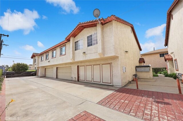 915 Carob Way Unit 2, Montebello, CA 90640 - rear view of property featuring concrete driveway, stucco siding, and an attached garage