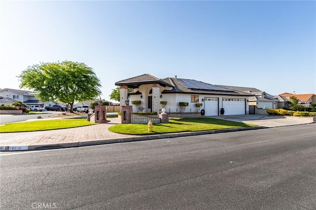 18016 Mariner Dr, Victorville, CA 92395 - view of front of home with concrete driveway, an attached garage, roof mounted solar panels, stucco siding, and a residential view