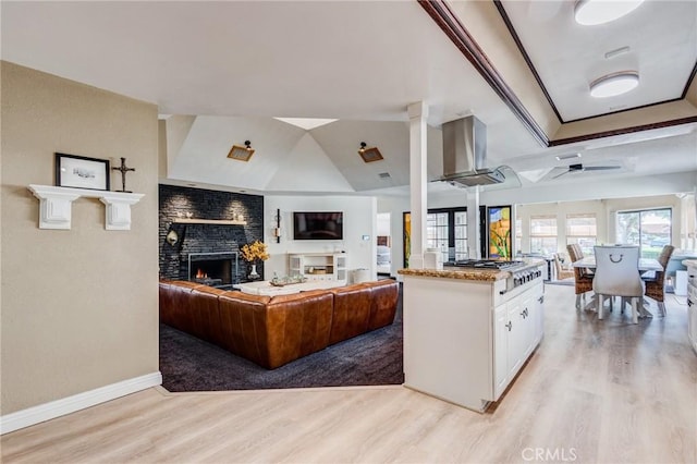 18016 Mariner Dr, Victorville, CA 92395 - kitchen featuring light wood-style floors, open floor plan, white cabinets, a ceiling fan, and a large fireplace