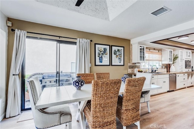 18016 Mariner Dr, Victorville, CA 92395 - dining area featuring light wood-style floors, a textured ceiling, and a skylight