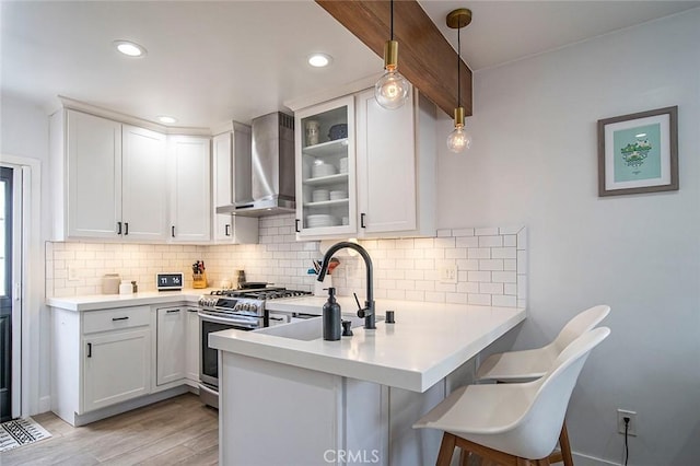 4218 E 3rd St, Long Beach, CA 90814 - kitchen with stainless steel range with gas stovetop, wall chimney exhaust hood, a peninsula, tasteful backsplash, and light countertops