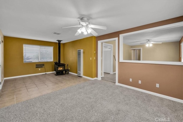 50350 Quailbush Rd, Johnson Valley, CA 92285 - carpeted empty room with a ceiling fan, a wood stove, baseboards, and tile patterned floors