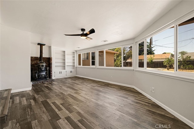 412 2nd St, Orland, CA 95963 - unfurnished living room featuring baseboards, a wood stove, a ceiling fan, dark wood-type flooring, and built in features