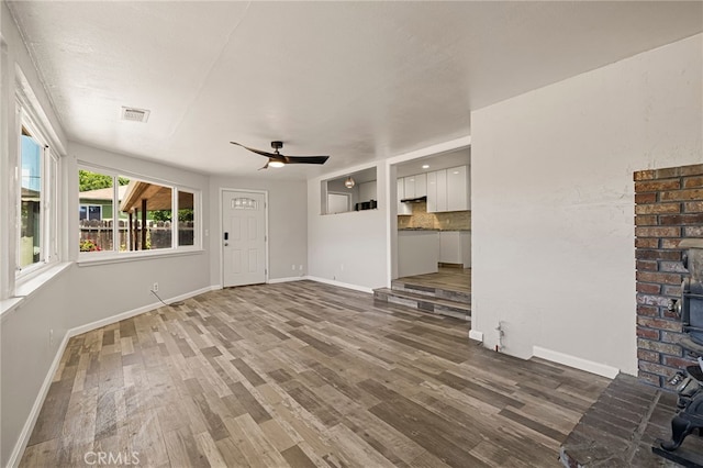 412 2nd St, Orland, CA 95963 - unfurnished living room with a wood stove, wood finished floors, baseboards, and a ceiling fan