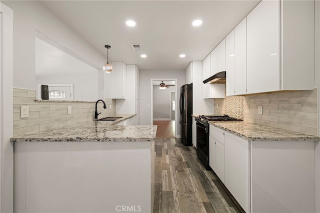 412 2nd St, Orland, CA 95963 - kitchen with black range with gas stovetop, a sink, under cabinet range hood, freestanding refrigerator, and a ceiling fan