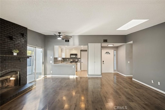 29247 Allan St, Lake Elsinore, CA 92532 - unfurnished living room with a ceiling fan, a textured ceiling, a skylight, light wood-type flooring, and baseboards