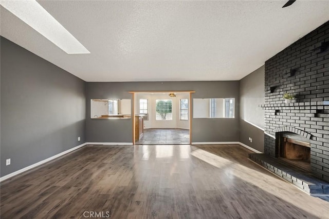 29247 Allan St, Lake Elsinore, CA 92532 - unfurnished living room with a textured ceiling, wood finished floors, a brick fireplace, baseboards, and a skylight
