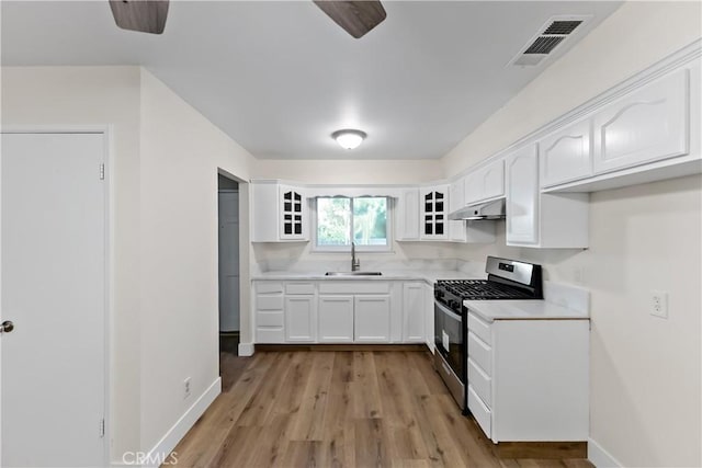 2131 W Pico Ave, Fresno, CA 93705 - kitchen with stainless steel gas stove, glass insert cabinets, under cabinet range hood, and white cabinets