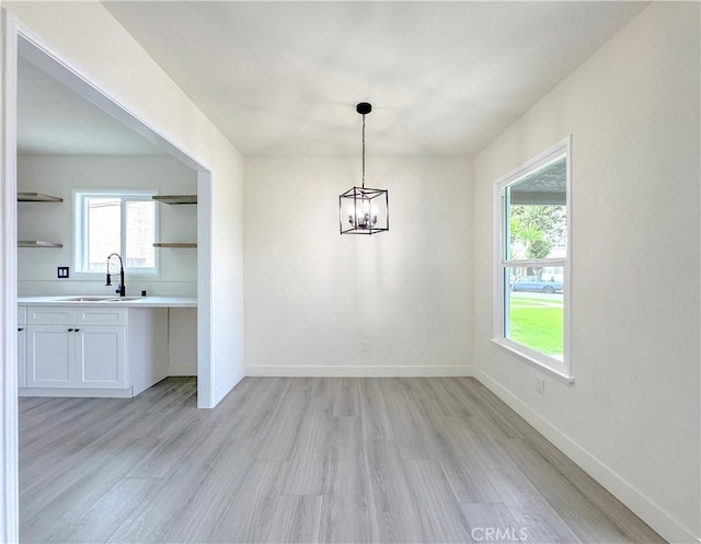 1512 S Butler Ave, Compton, CA 90221 - unfurnished dining area featuring a sink, light wood finished floors, a chandelier, and baseboards
