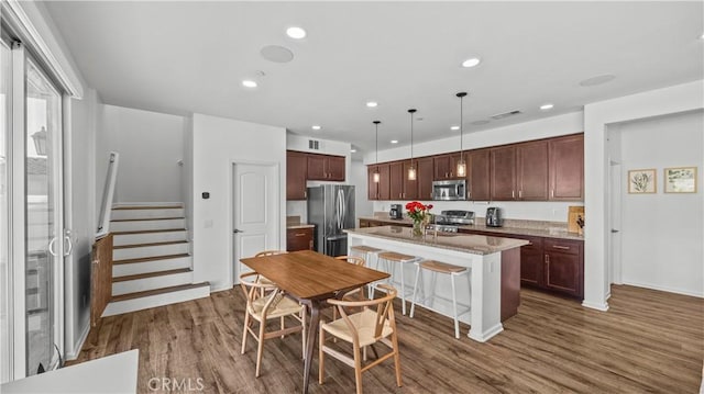 36434 Geranium Dr, Lake Elsinore, CA 92532 - kitchen with appliances with stainless steel finishes, dark wood-type flooring, a center island with sink, recessed lighting, and dark brown cabinetry