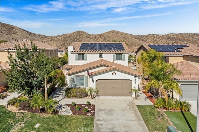 36434 Geranium Dr, Lake Elsinore, CA 92532 - mediterranean / spanish-style house with a tile roof, concrete driveway, stucco siding, a mountain view, and roof mounted solar panels