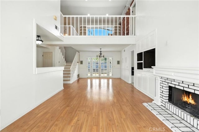28918 Lillyglen Dr, Canyon Country, CA 91387 - unfurnished living room featuring stairs, light wood finished floors, a warm lit fireplace, a high ceiling, and a chandelier