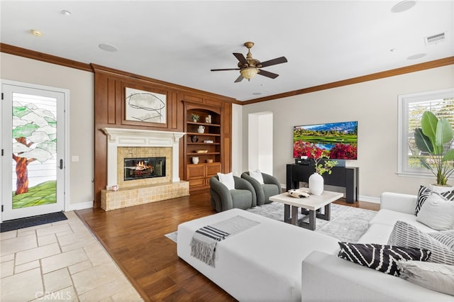 19103 Green Oaks Rd, Yorba Linda, CA 92886 - living room featuring a ceiling fan, crown molding, a tiled fireplace, built in shelves, and wood finished floors