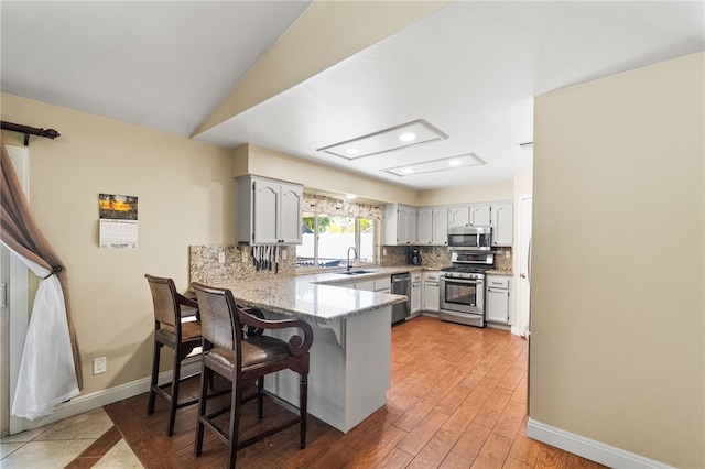 32642 Durango Ct, Wildomar, CA 92595 - kitchen with stainless steel appliances, a peninsula, tasteful backsplash, a sink, and a breakfast bar area