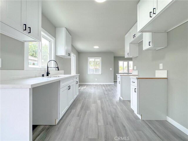 1976 E 112th St, Los Angeles, CA 90059 - kitchen featuring a sink, light wood-style flooring, baseboards, and white cabinetry