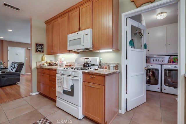 4002 Camerino St, Lakewood, CA 90712 - kitchen featuring white appliances, washer and clothes dryer, light tile patterned flooring, light stone countertops, and recessed lighting