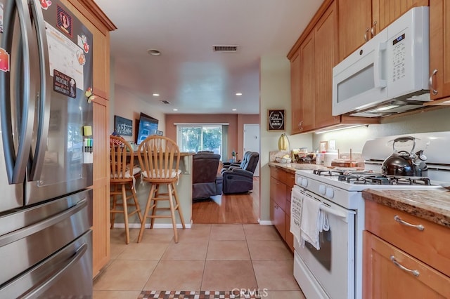 4002 Camerino St, Lakewood, CA 90712 - kitchen featuring white appliances, light tile patterned floors, open floor plan, light stone counters, and brown cabinets