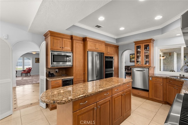 1738 N Ukiah Way, Upland, CA 91784 - kitchen featuring arched walkways, stainless steel appliances, light tile patterned flooring, a tray ceiling, and light stone countertops