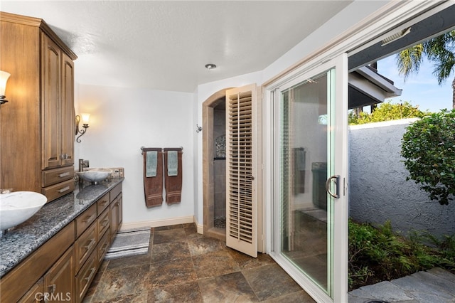 1738 N Ukiah Way, Upland, CA 91784 - full bathroom featuring stone finish floors, a shower stall, double vanity, and baseboards