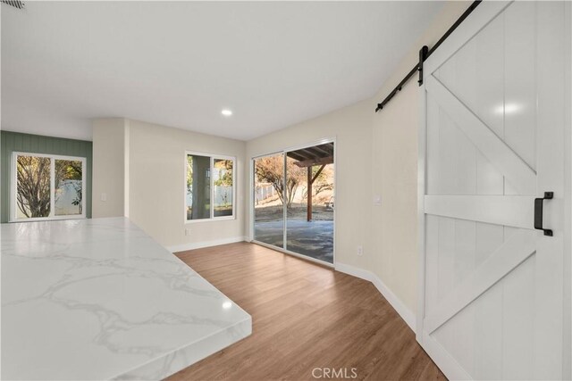 31832 Poole Ct, Temecula, CA 92591 - unfurnished dining area with a barn door, baseboards, wood finished floors, plenty of natural light, and recessed lighting