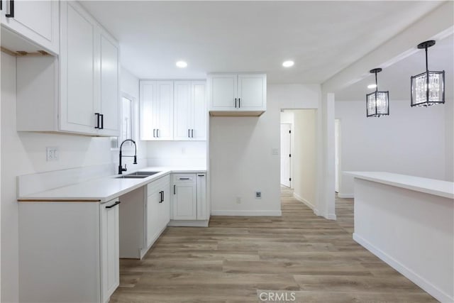 1342 W Magnolia St, Compton, CA 90220 - kitchen featuring a sink, white cabinetry, light wood-style floors, recessed lighting, and decorative light fixtures