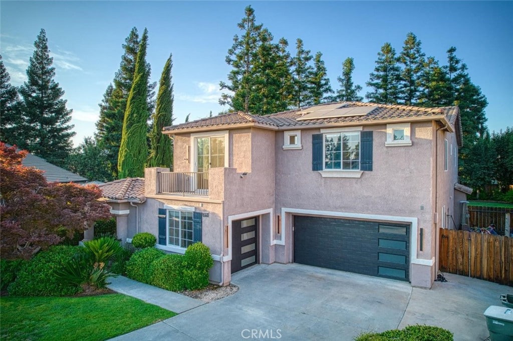 2696 E Solar Ave, Fresno, CA 93720 - view of front facade with an attached garage, roof mounted solar panels, stucco siding, and driveway