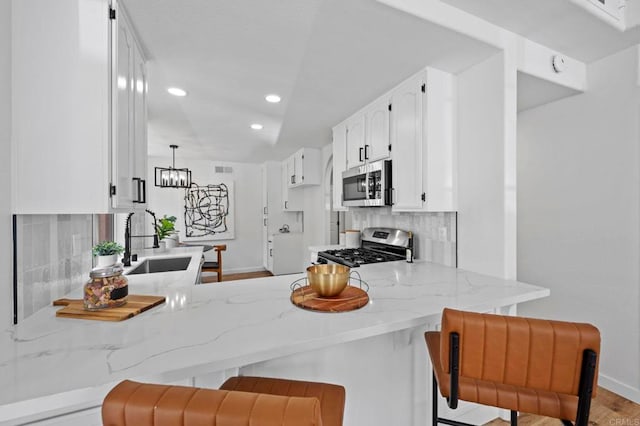 3581 Cameo Dr Unit 35, Oceanside, CA 92056 - kitchen featuring stainless steel appliances, a peninsula, light stone countertops, tasteful backsplash, and white cabinets