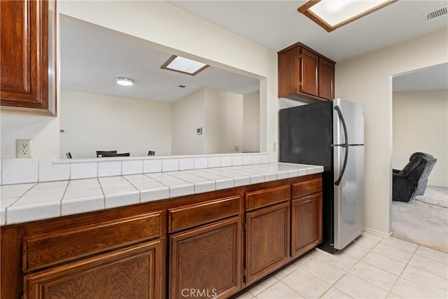 42330 61st St W, Lancaster, CA 93536 - kitchen featuring freestanding refrigerator, light tile patterned flooring, and brown cabinetry
