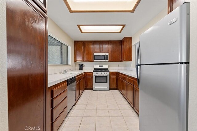 42330 61st St W, Lancaster, CA 93536 - kitchen with stainless steel appliances, light tile patterned flooring, a sink, tile countertops, and brown cabinets