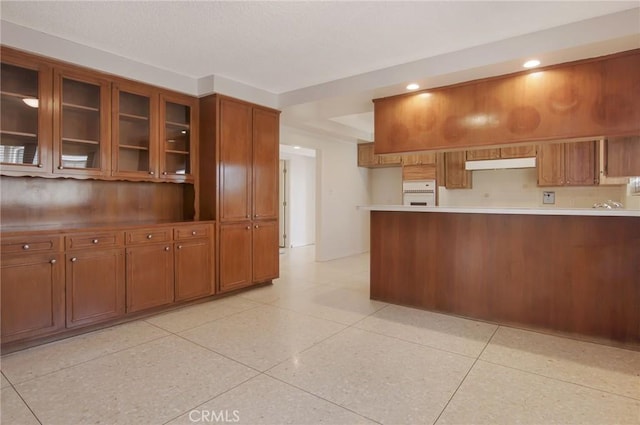 4612 W 132nd St, Hawthorne, CA 90250 - kitchen with under cabinet range hood, brown cabinetry, glass insert cabinets, light countertops, and recessed lighting