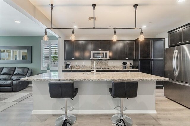 29042 Botanical Cir, Menifee, CA 92584 - kitchen featuring stainless steel appliances, a breakfast bar area, open floor plan, light stone countertops, and pendant lighting