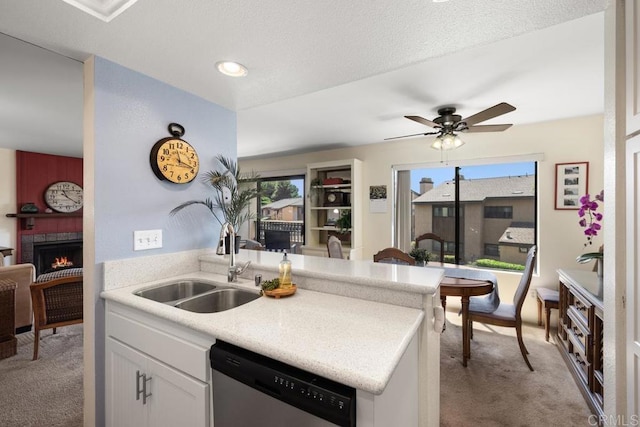 7780 Parkway Dr Unit 703, La Mesa, CA 91942 - kitchen with stainless steel dishwasher, a sink, light carpet, a warm lit fireplace, and white cabinets